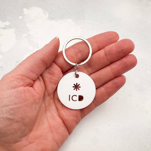 lightweight white acrylic round keychain with 'ICD' laser cut out, held in a hand