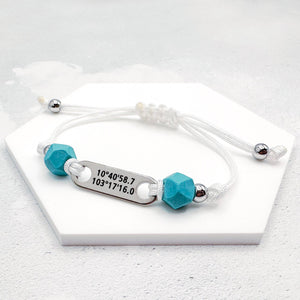 Bracelet with turquoise beads and a silver tag on a white surface