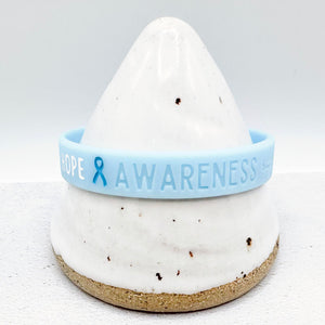 light blue awareness ribbon wristband with "hope & awareness" text engraved on its side 