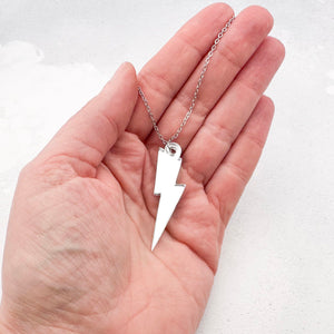 Silver acrylic lightning bolt necklace held in a hand 