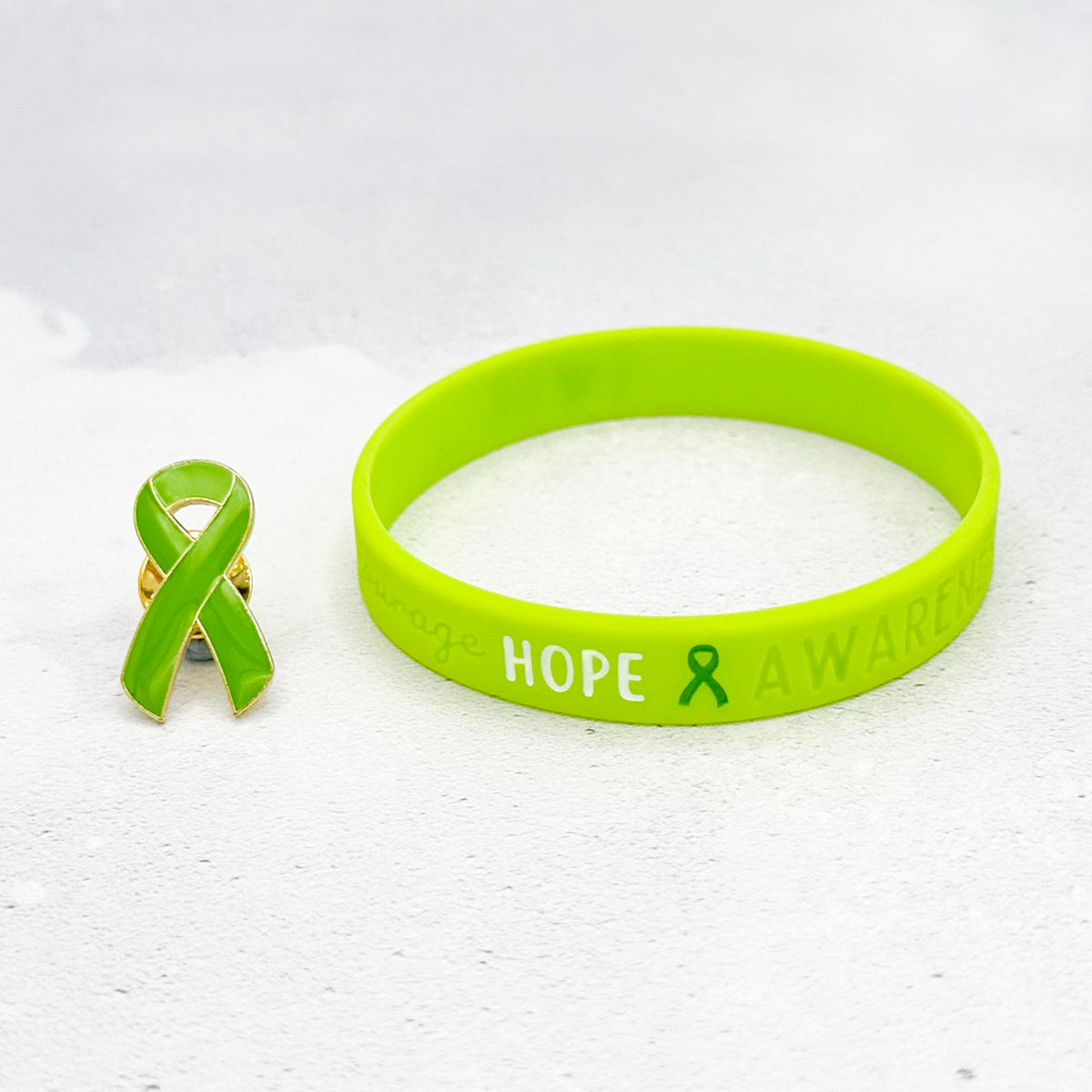 Lime green silicone wristband engraved with ‘Hope & Awareness’ beside matching lime green enamel ribbon pin