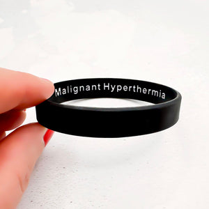 Black wristband with 'Malignant Hyperthermia' text held by a hand on a white background