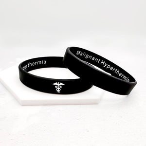 Two black wristbands with malignant hyperthermia text on the inside and white caduceus symbol on a white background