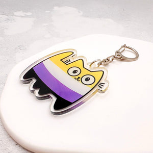 A cute acrylic keychain shaped like a cat in the nonbinary flag colours