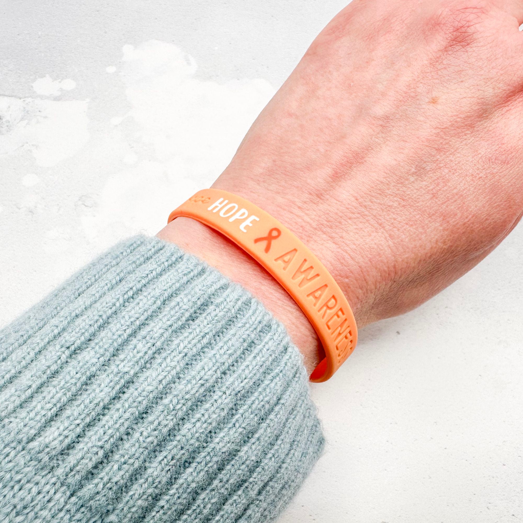 orange silicone wristband engraved with ‘Hope & Awareness’ worn on person's wrist