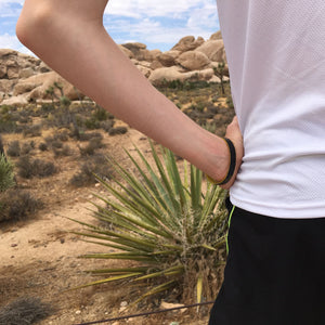 Person in a desert landscape with cacti and rocky terrain wearing medical bracelet