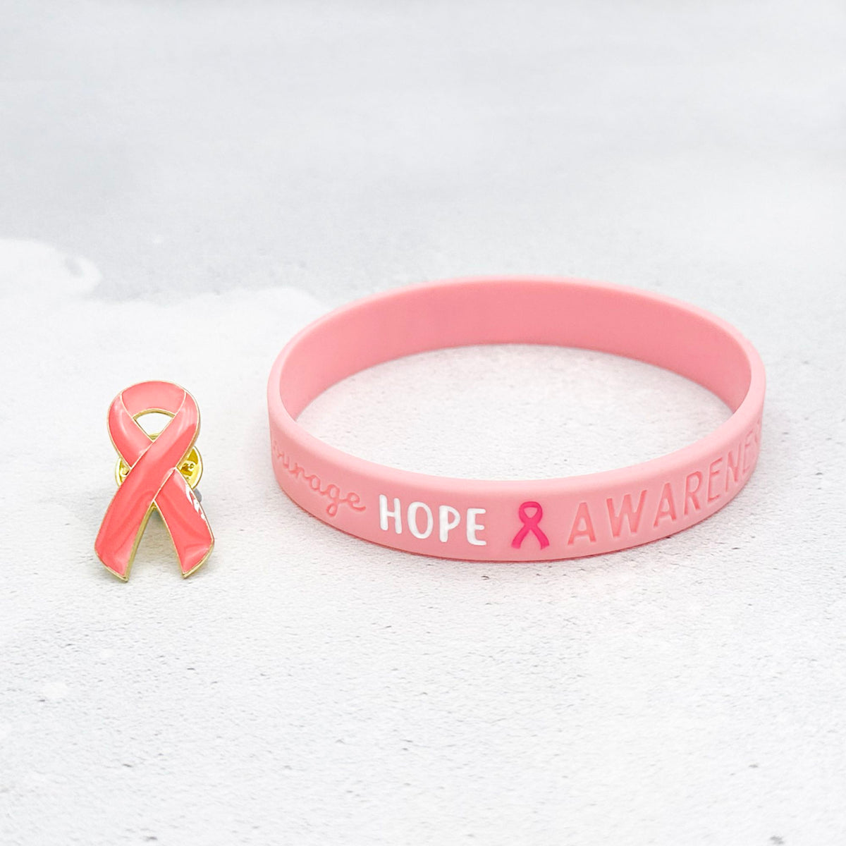 pink silicone wristband engraved with ‘Hope & Awareness’ besides matching pink enamel ribbon pin