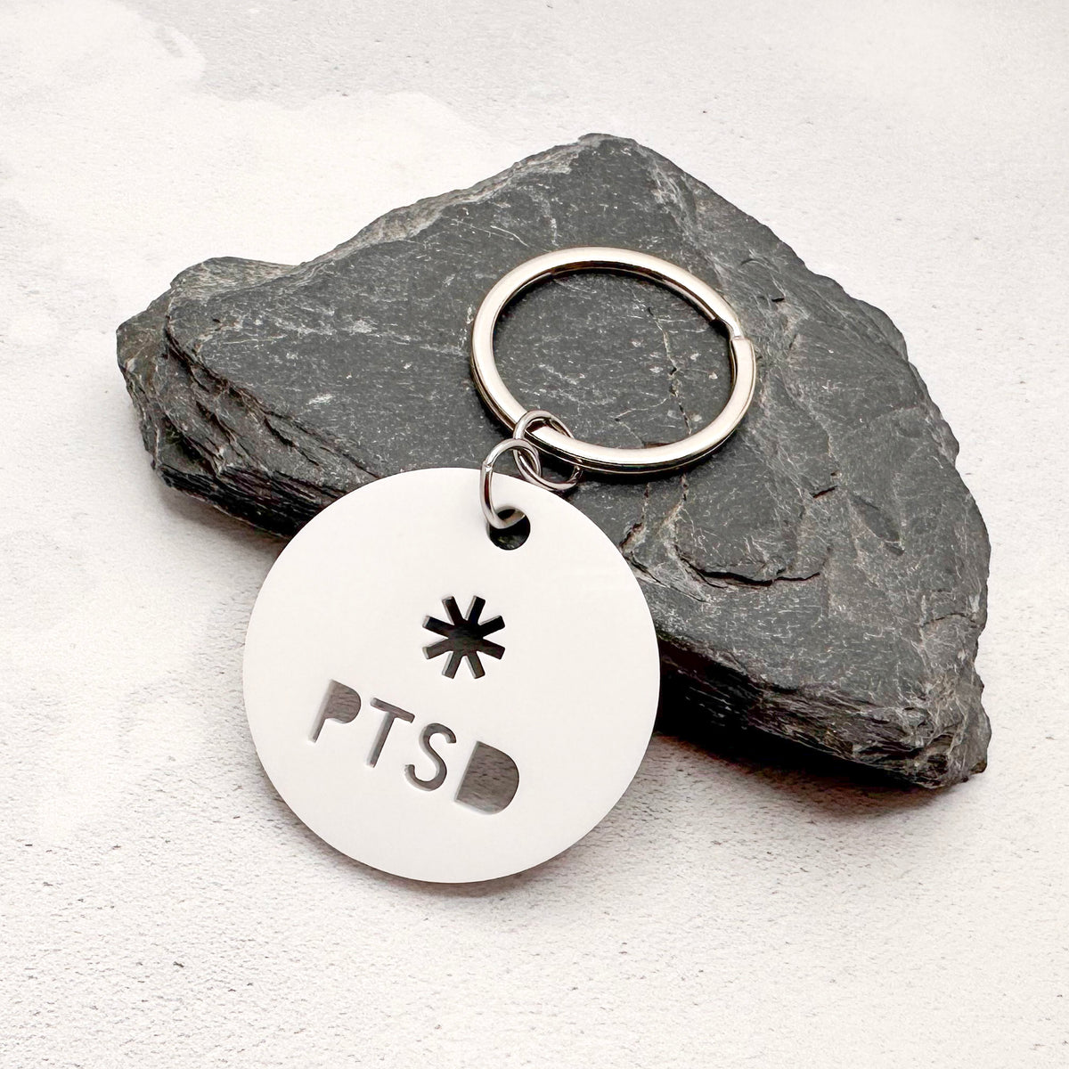 lightweight white acrylic round keychain with 'PTSD' laser cut out