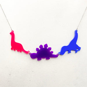 Necklace with three dinosaur-shaped pendants in bold bisexual colours of pink, purple, and blue, on a white background.