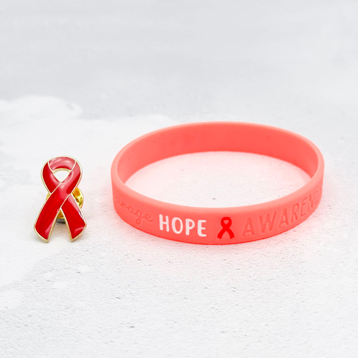 red silicone wristband engraved with ‘Hope & Awareness’ besides matching red enamel ribbon pin