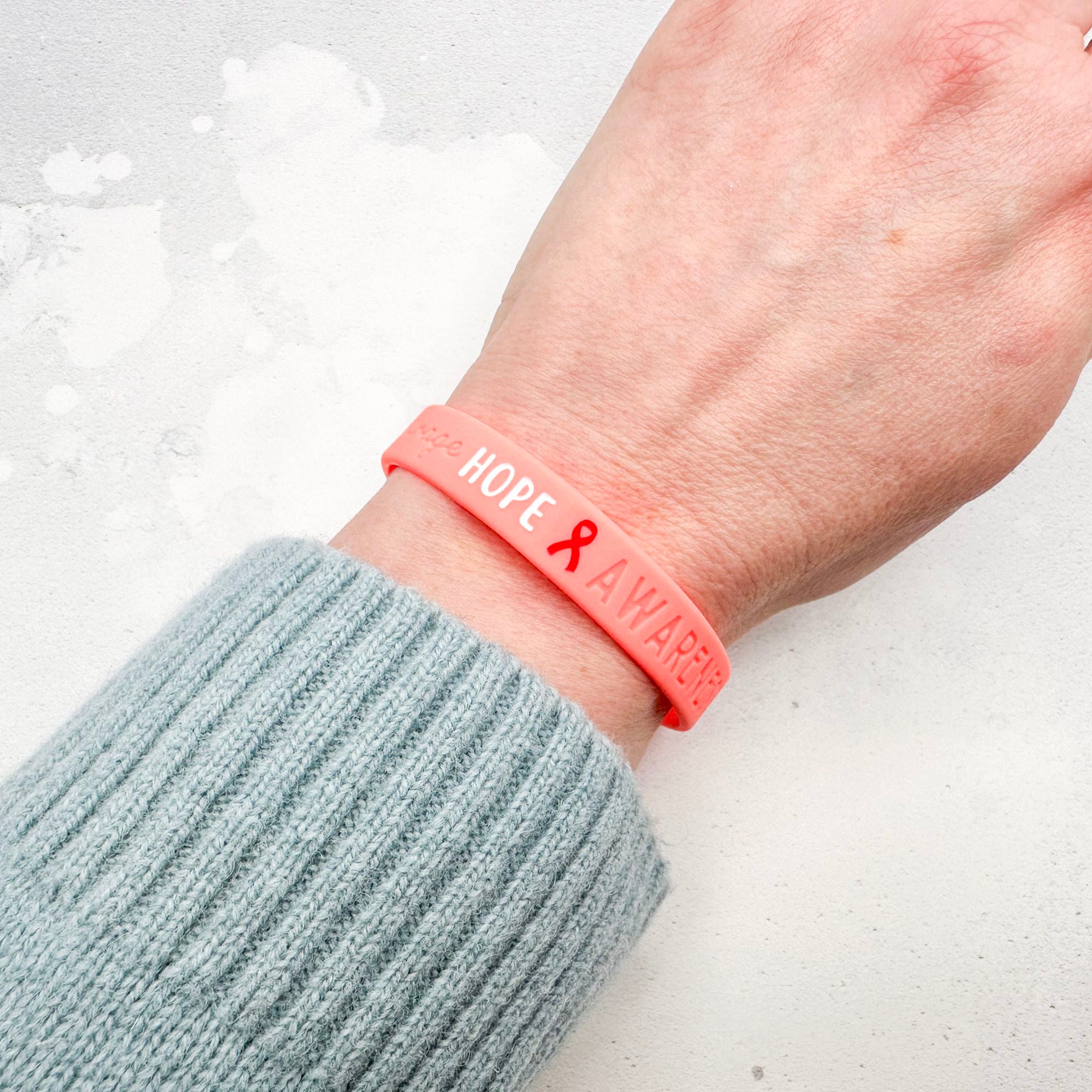red silicone wristband engraved with ‘Hope & Awareness’ worn on person's wrist