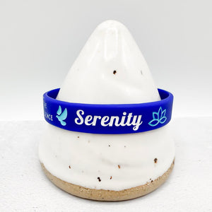 A blue silicone wristband with 'Serenity' and a peace sign printed in white and light blue