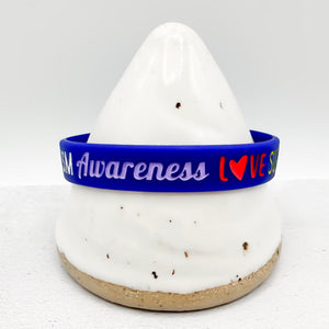 A blue silicone wristband with 'Awareness LOVE Support' printed in white and red