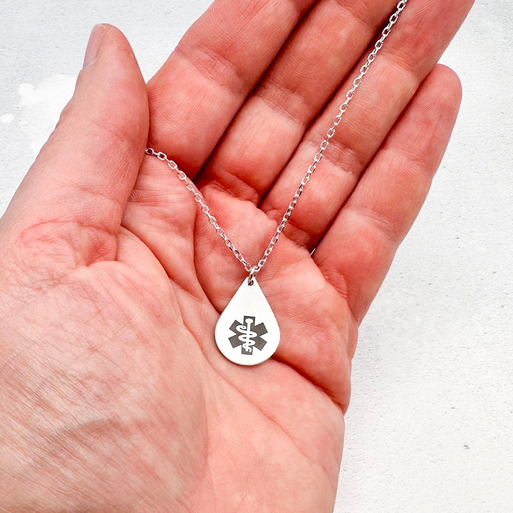 sterling silver medical alert necklace with star of life symbol on a teardrop-shaped pendant held in a hand