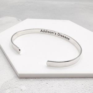 Silver bracelet with 'Addison's Disease' engraving on a white surface
