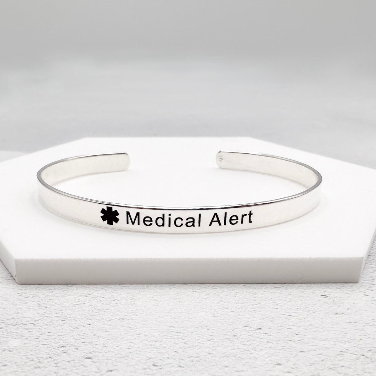 Silver medical alert cuff bracelet on a white background