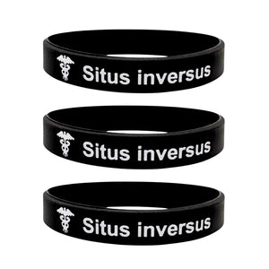 Three black silicone wristbands stacked vertically, each with the white text 'Situs inversus' and a small caduceus symbol