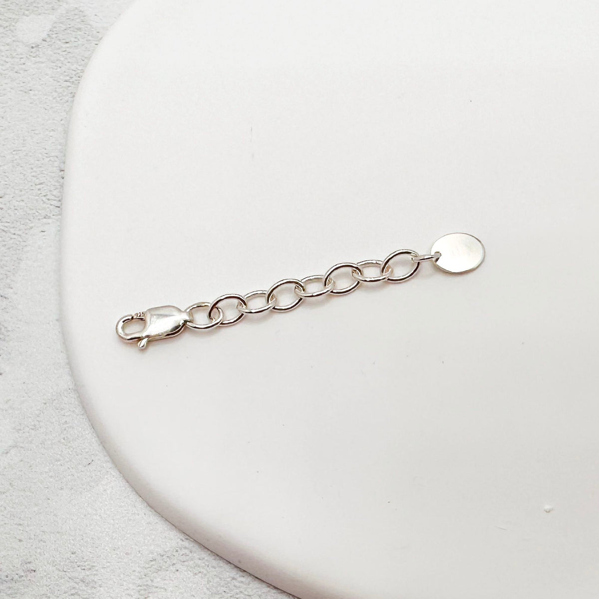 Sterling silver chain extender with a lobster clasp and a flat oval tag