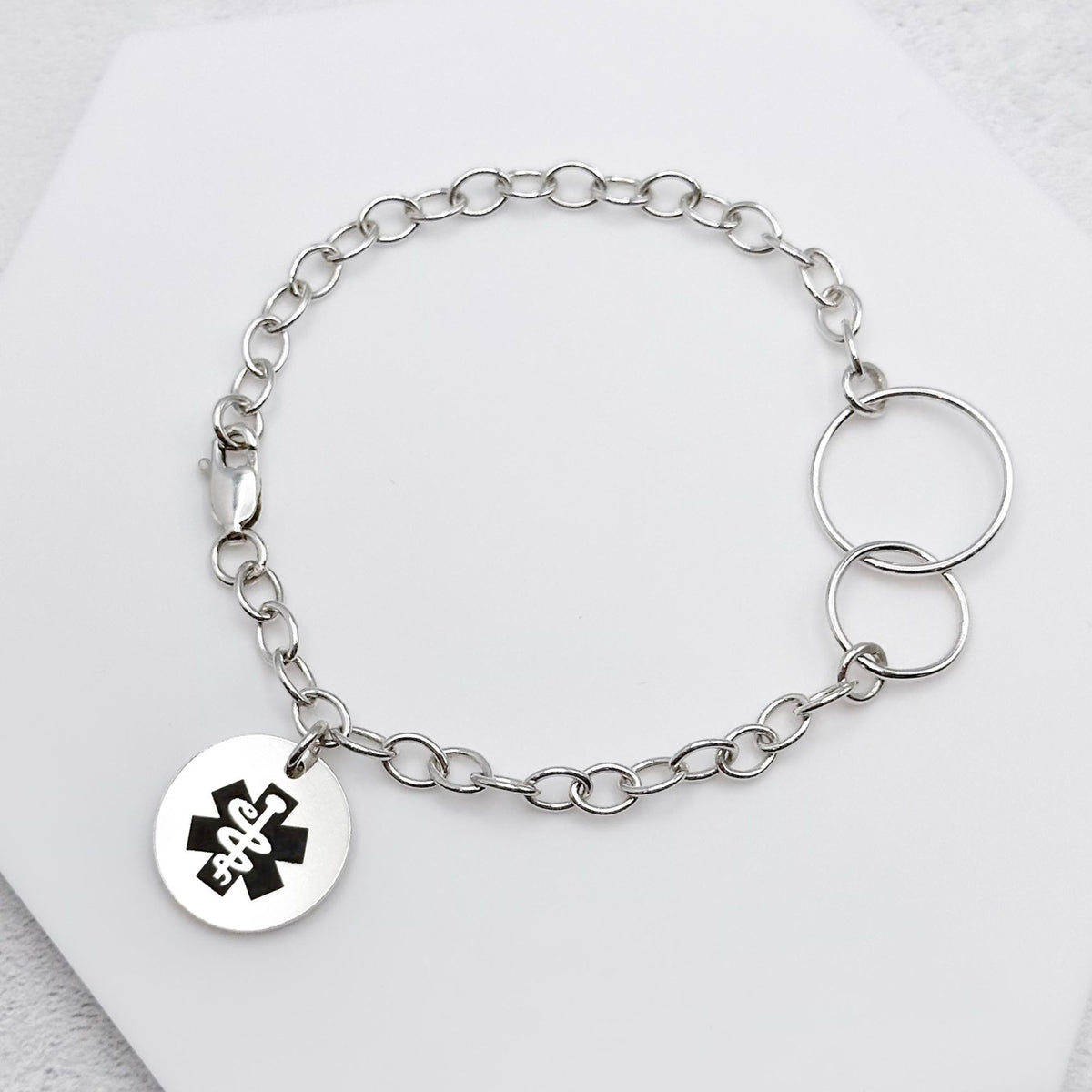 sterling silver chain bracelet with a round tag featuring the star of life medical symbol on a light background