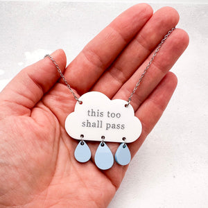 'This too shall pass' necklace with hand-painted acrylic cloud and raindrops held in hand