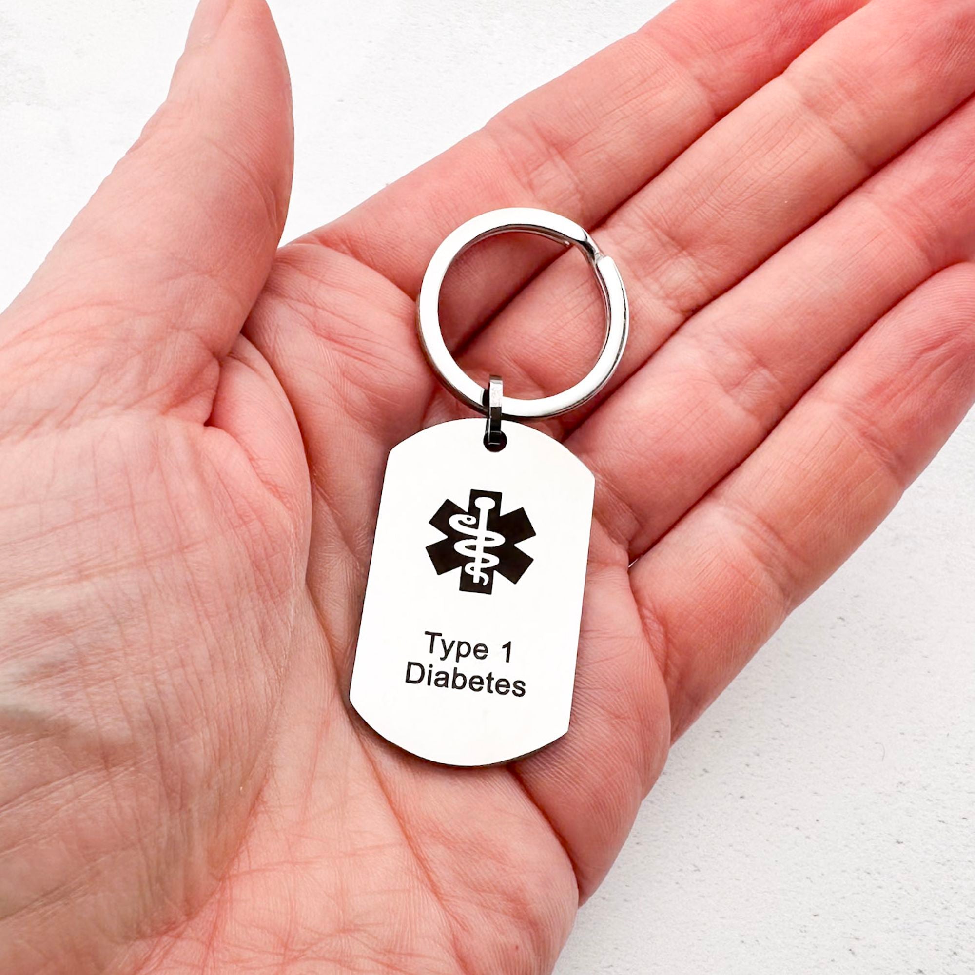 stainless steel keychain with star of life medical symbol and 'Type 1 Diabetes' text held in hand