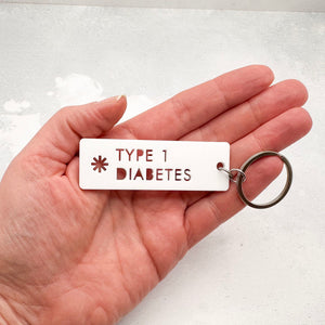 Acrylic Type 1 diabetes medical alert keychain with laser-cut text and silver keyring held in hand