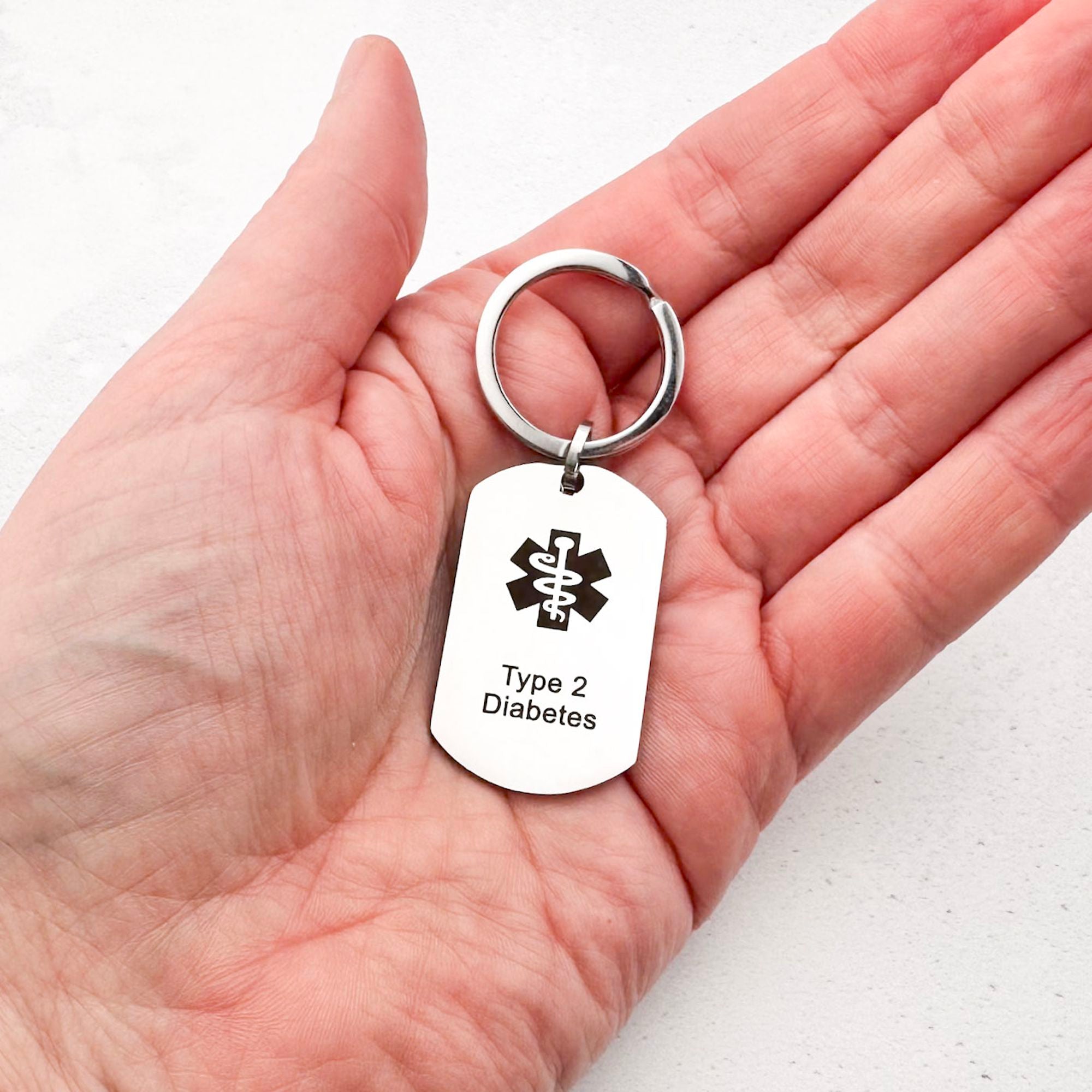 stainless steel keychain with star of life medical symbol and 'Type 2 Diabetes' text held in hand