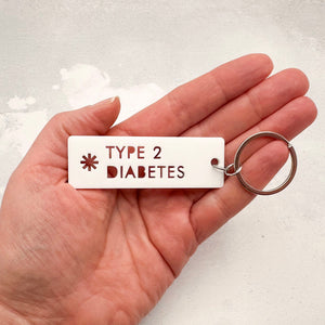 Type 2 Diabetes medical ID keyring shown in hand for size reference 25mm by 75mm rectangle