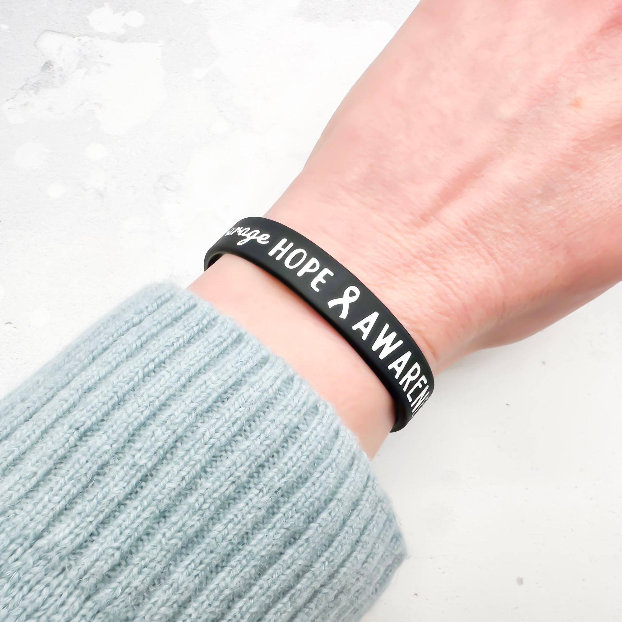 black and white silicone wristband engraved with ‘Hope & Awareness’ worn on person's wrist